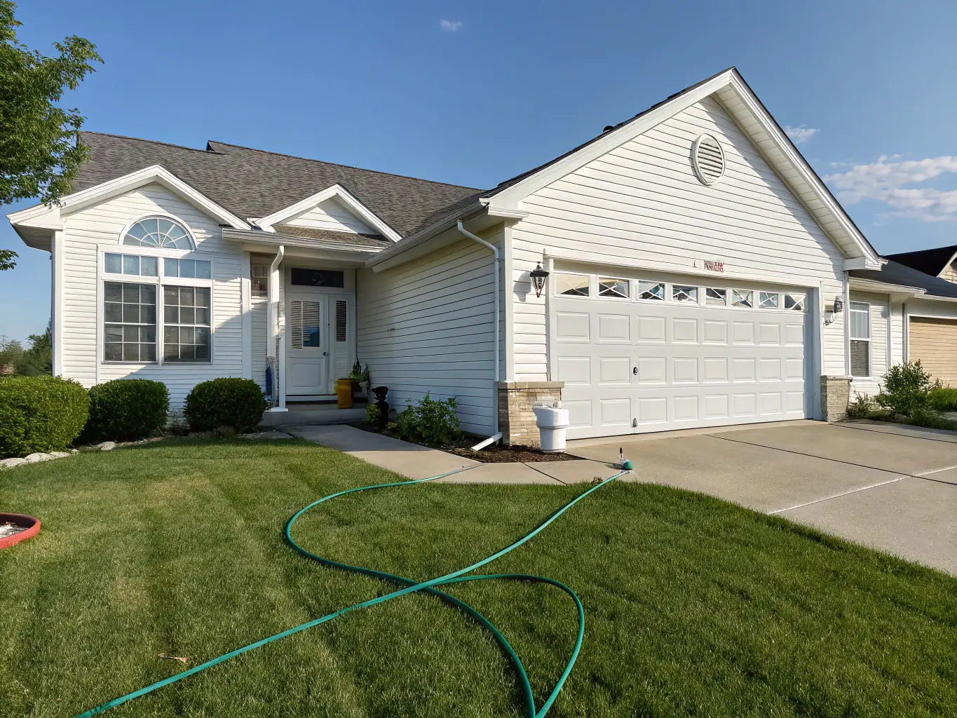 A residential house with clean siding after a power washing service, showcasing the removal of dirt and grime, taken on a sunny day in Long Island, NY.
